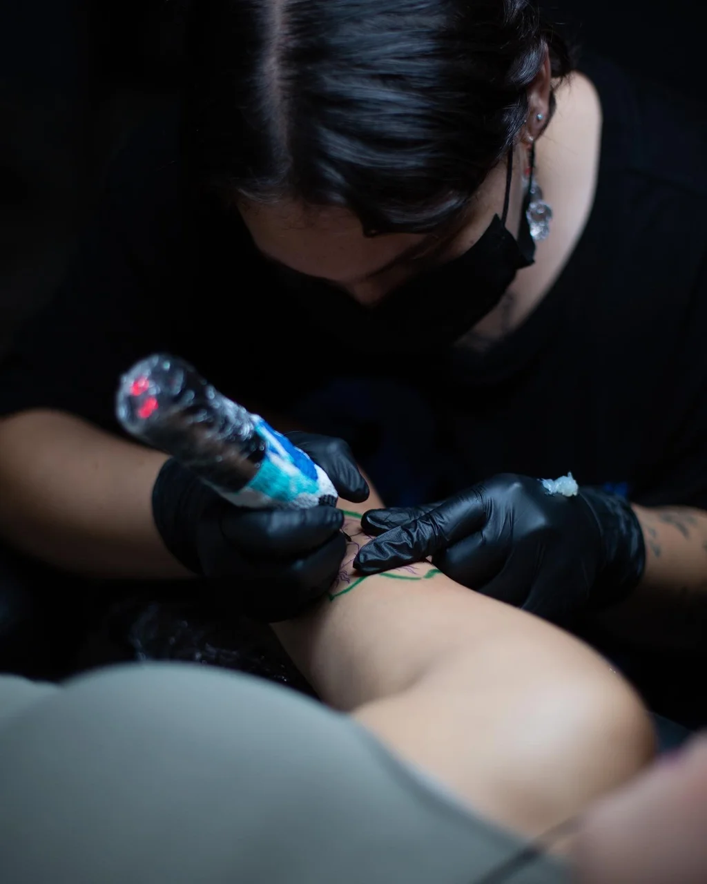 Claudia Flocco tattooing in the studio in low key lighting